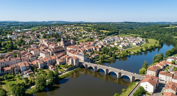 Photographie aérienne ou vue panoramique de la ville d'Aixe-sur-Vienne montrant ses caractéristiques urbaines et architecturales distinctives (centre-ville, zones résidentielles, paysage local de Haute-Vienne avec ses bâtiments, rues et environnement naturel environnant), avec une esthétique professionnelle et moderne, sans texte, logo ou filigrane. L'image doit clairement représenter le cadre géographique local et permettre d'identifier la commune comme une zone d'intervention de l'entreprise.