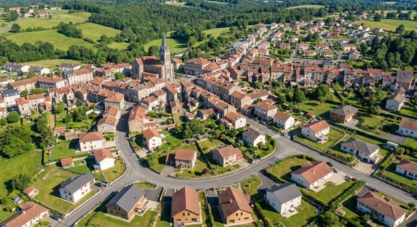 Photographie aérienne ou vue panoramique de la commune d'Ambazac en Haute-Vienne, montrant ses caractéristiques urbaines et architecturales distinctives (centre-ville, bâtiments résidentiels, paysage local avec ses rues et environnement naturel environnant). L'image doit avoir une esthétique professionnelle et moderne, sans texte, logo ou filigrane, et permettre d'identifier clairement Ambazac comme une zone d'intervention de l'entreprise de menuiserie.